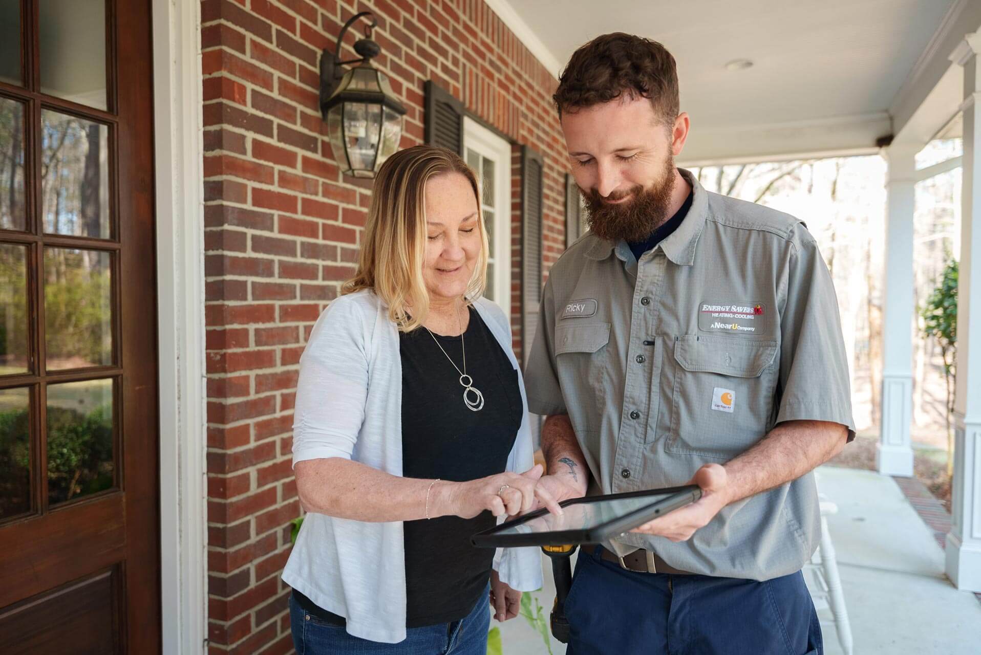 an-energy-savers-technician-reviewing-an-item-on-a-digital-tablet-with-a-customer