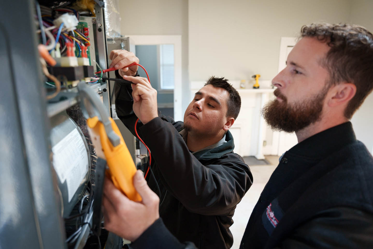 Two technicians performing diagnostic tests on a customer’s home HVAC unit.