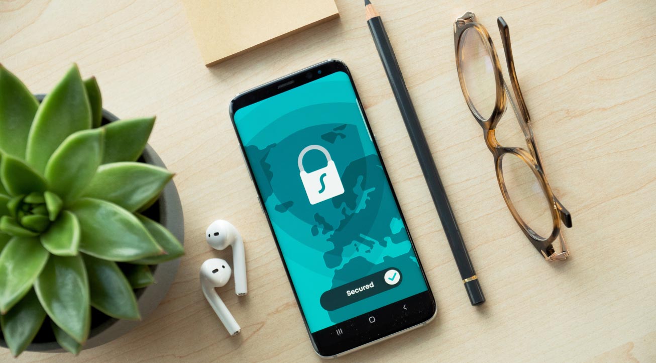 A photo of a phone and various items on a desk. The phone screen has a padlock icon and “secured” on it.